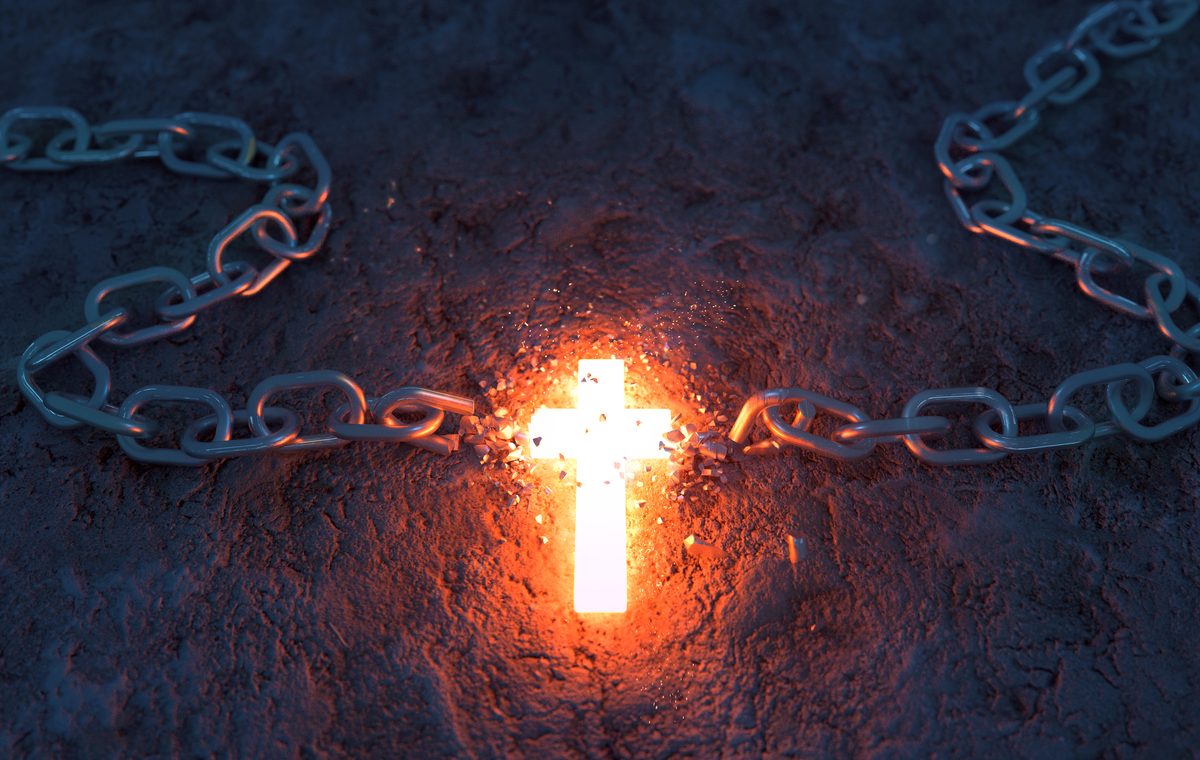 A bright glowing cross is breaking a metal chain